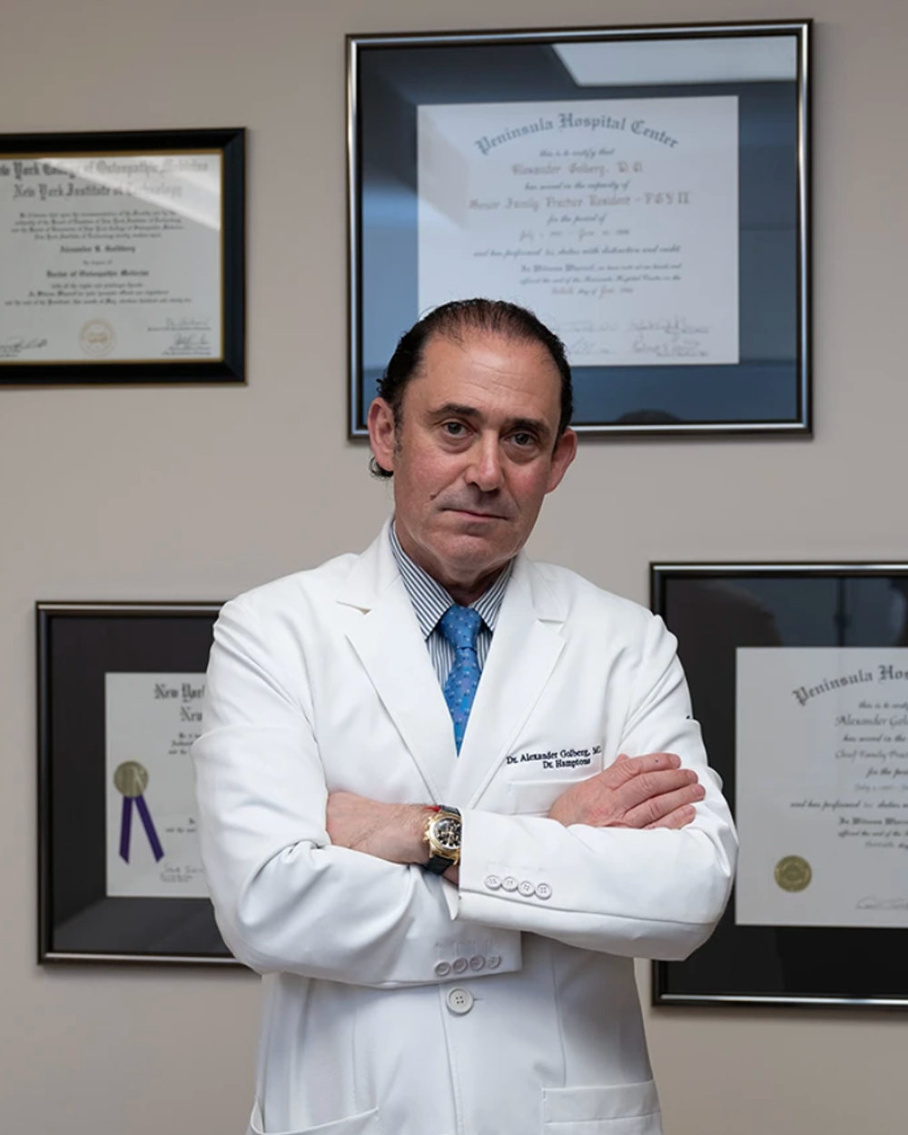 Dr. Alexander Golberg, MD, DO, founding physician of DoctorNYC, photographed in his consultation room beside his medical diplomas